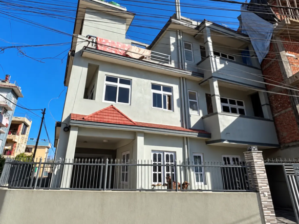 Modern house in kathmandu with a gated entrance and surrounding residential buildings.
