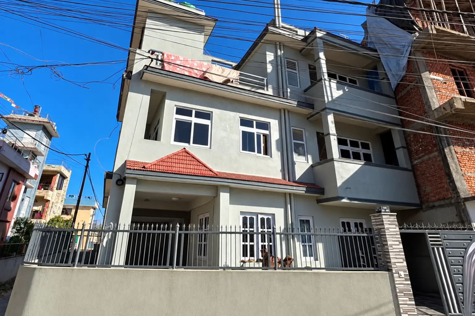 Modern house in kathmandu with a gated entrance and surrounding residential buildings.
